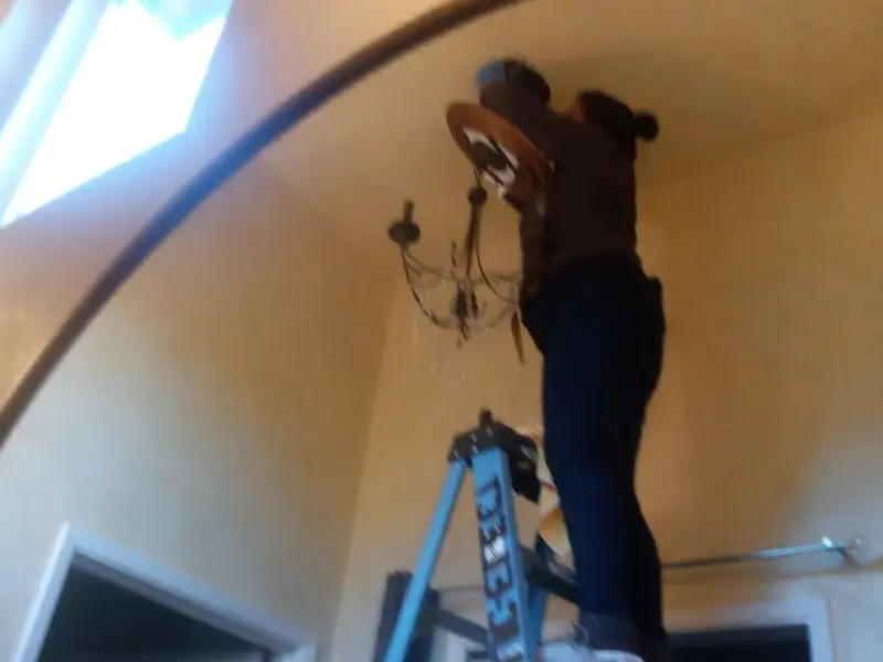 Electrician installing a chandelier in a Baldwin Park residence